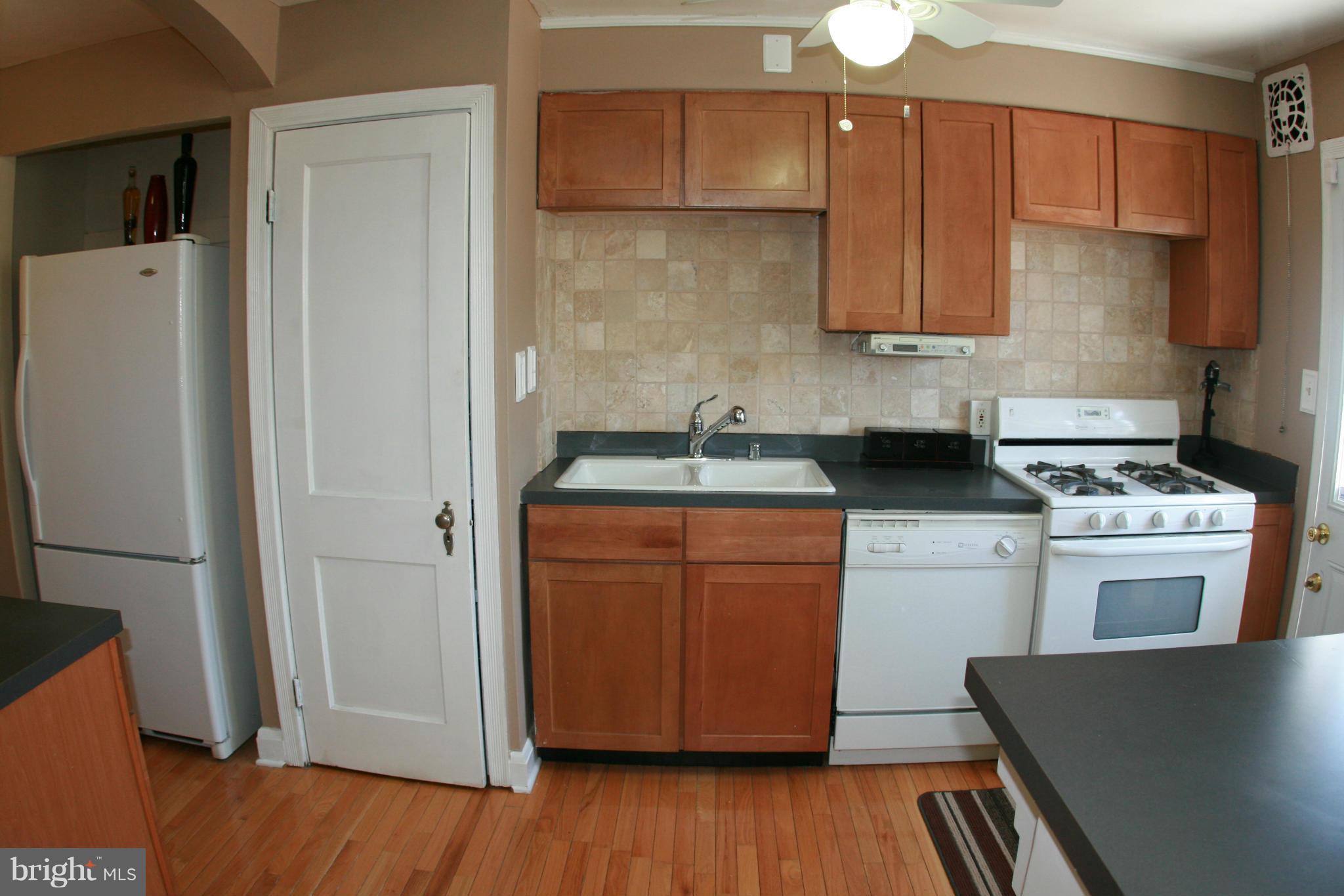 429 Academy Road Catonsville, MD 21228 - Photo 10 of 26 a kitchen with stainless steel appliances granite countertop a refrigerator a stove a sink and white countertops with wooden floor