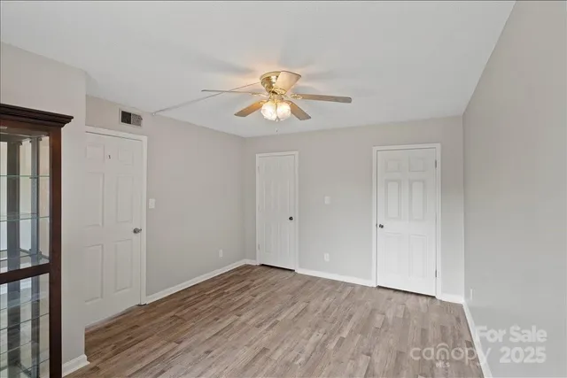 a view of room with hardwood floor and a ceiling fan