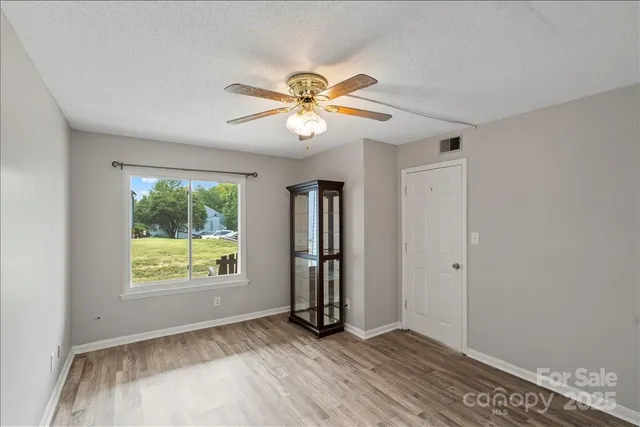a view of an empty room with window and chandelier fan