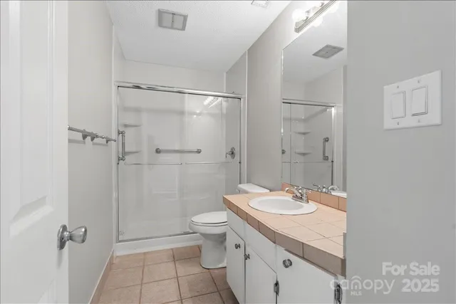 a bathroom with a granite countertop sink a toilet and shower