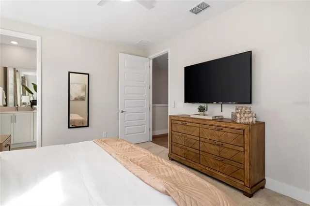 a bedroom with a bed and a flat screen tv in white walls