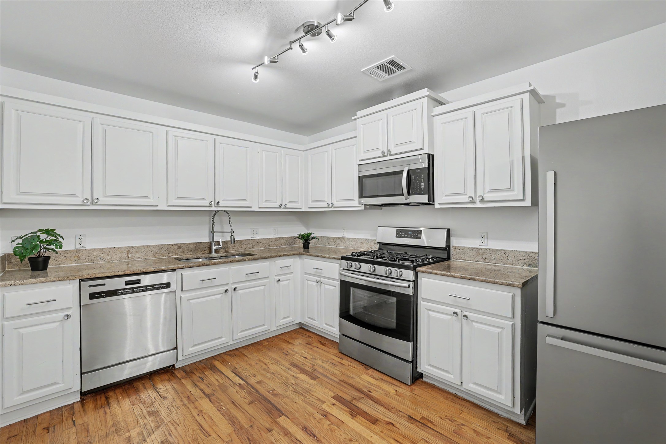 6307 Chesterfield Avenue Austin, TX 78752 - Photo 3 of 20 a kitchen with stainless steel appliances granite countertop a stove top oven a sink and white cabinets