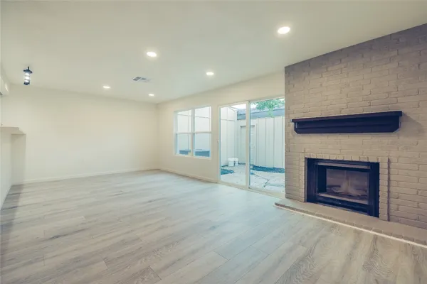 an empty room with wooden floor fireplace and windows