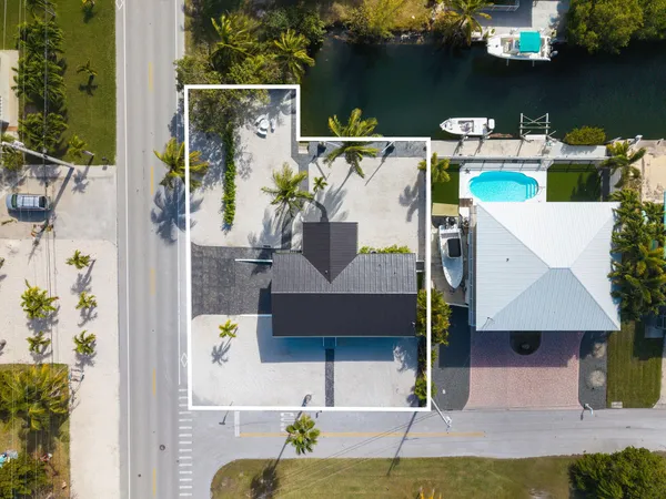 an aerial view of a house with swimming pool and glass top table and chair