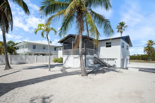a view of a house with a yard and palm trees