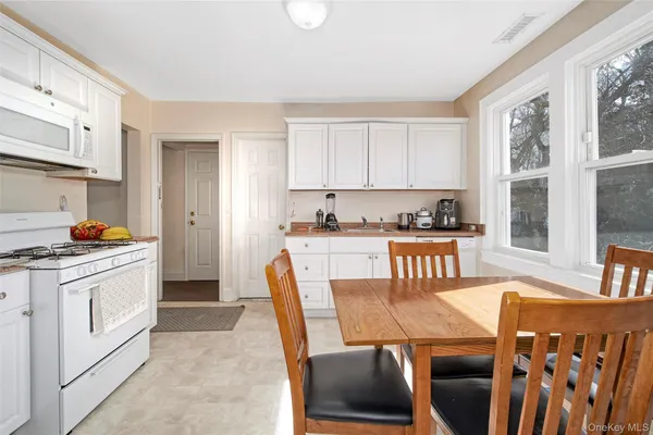 a kitchen with stainless steel appliances granite countertop a stove a refrigerator a dining table and chairs with wooden floor