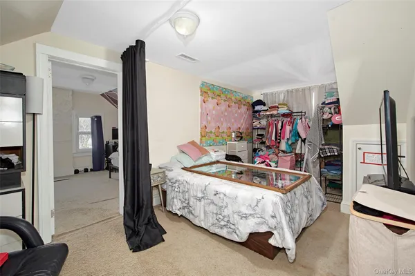 a bedroom with bed and a flat tv screen on dresser