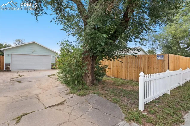 a view of a house with a large tree and wooden fence