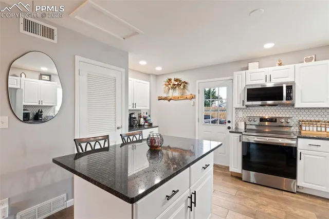 a kitchen with stainless steel appliances granite countertop a sink a stove and a microwave