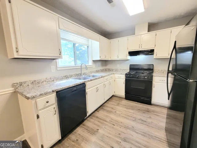 a kitchen with granite countertop white cabinets and white appliances