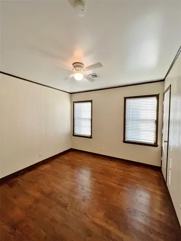 an empty room with wooden floor chandelier and windows