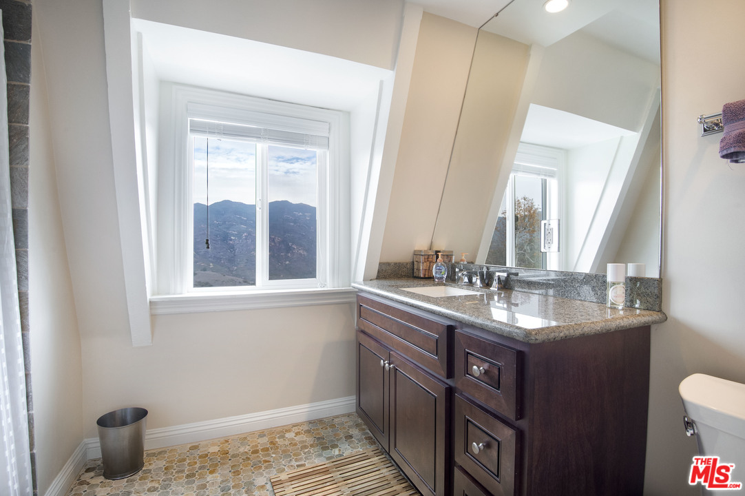 26258 Fairside Road Malibu, CA 90265 - Photo 23 of 46 a bathroom with a granite countertop sink a mirror and a toilet