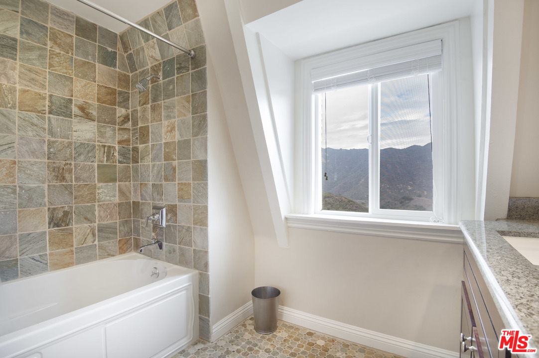 26258 Fairside Road Malibu, CA 90265 - Photo 26 of 46 a bathroom with a granite countertop bathtub a window and a shower