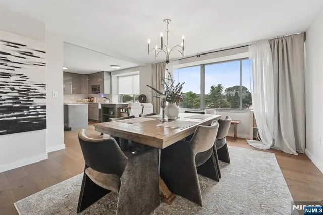 a dining room with wooden floor a chandelier a wooden table and chairs