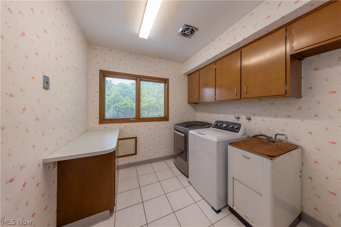25001 Letchworth Road Beachwood, OH 44122 - Photo 22 of 50 Laundry room featuring white square tile flooring, wood-finish cabinetry, a utility sink, and a window with wood-frame trim