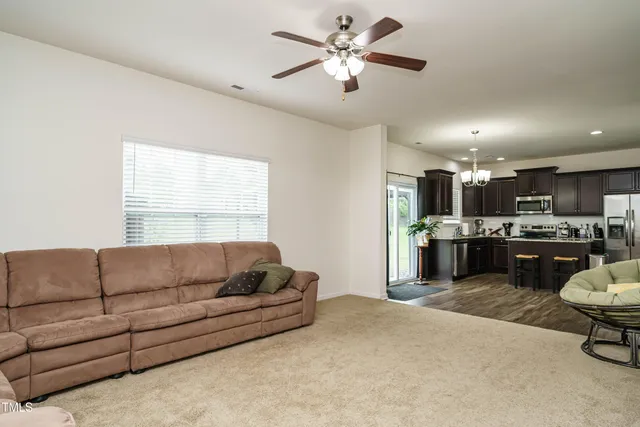a living room with furniture kitchen area and a window