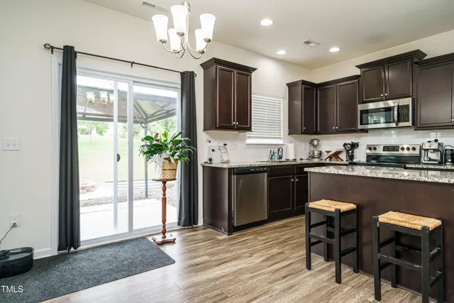 a kitchen with kitchen island granite countertop wooden floors and stainless steel appliances