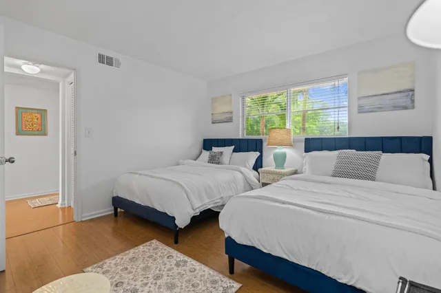 a bedroom with two beds and a dresser next to a window