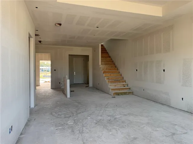 a view of an empty room with wooden floor and staircase