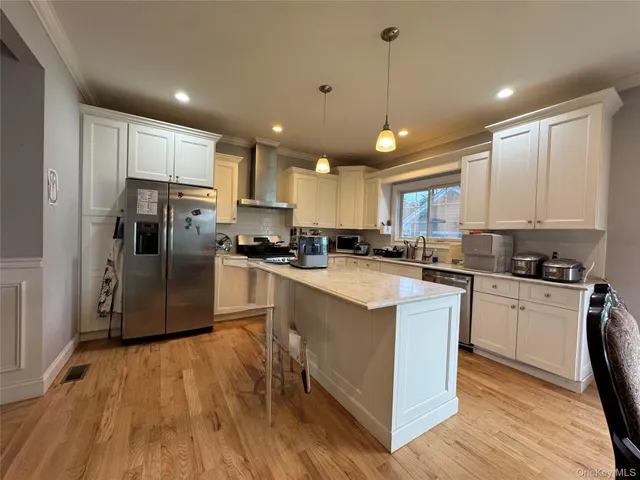 a kitchen with stainless steel appliances granite countertop a refrigerator a sink dishwasher a stove and white countertops with wooden floor