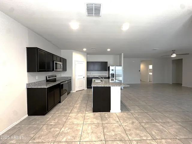 a kitchen with kitchen island granite countertop a sink and refrigerator