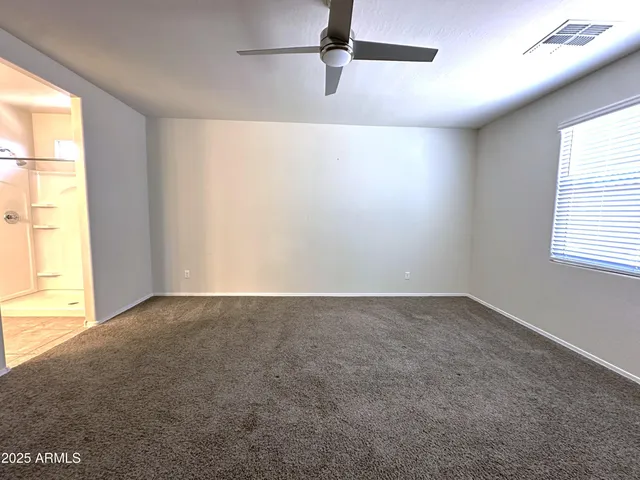 an empty room with a ceiling fan and a window