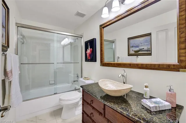 a bathroom with a granite countertop sink toilet a mirror and shower