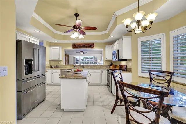 a kitchen with stainless steel appliances granite countertop a dining table chairs stove a refrigerator and a chandelier