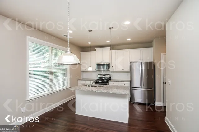 a kitchen with a refrigerator a sink and wooden floor