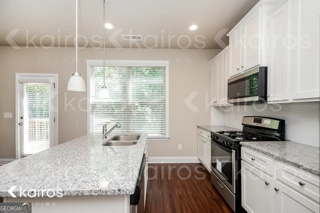 a kitchen with stainless steel appliances granite countertop a stove a sink and a microwave