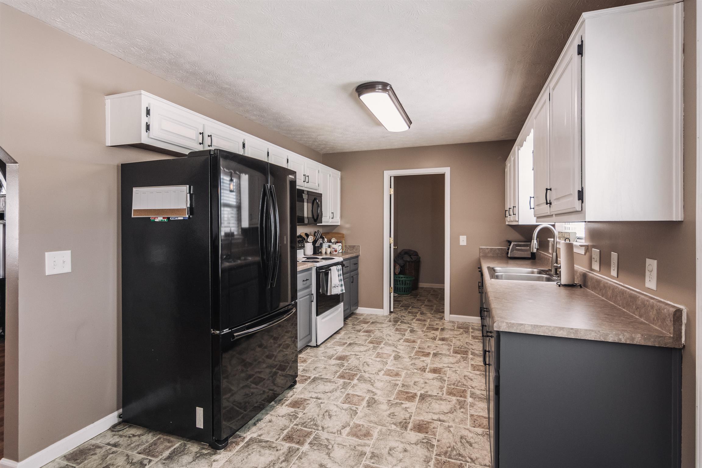 399 Corinth Road Portland, TN 37148 - Photo 10 of 28 a kitchen with granite countertop a refrigerator and a sink