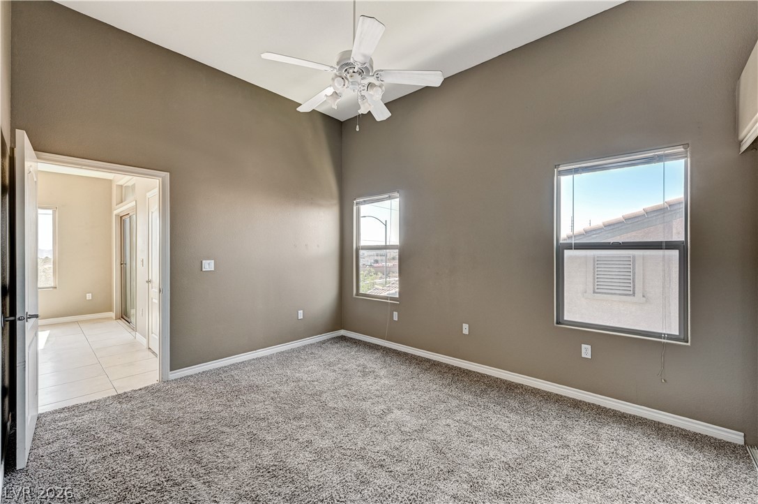 8985 South Durango Drive, Unit 2187 Las Vegas, NV 89113 - Photo 15 of 73 A tranquil primary bedroom with vaulted ceilings, featuring soft carpeting and a clear passage to a bright, tiled en-suite.