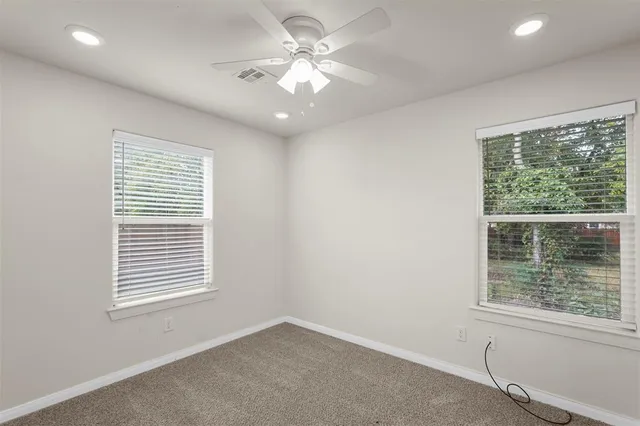 an empty room with windows and fan