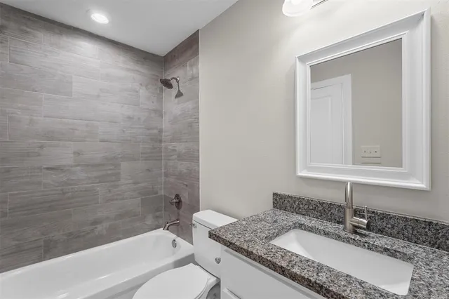 a bathroom with a granite countertop sink mirror toilet and bathtub