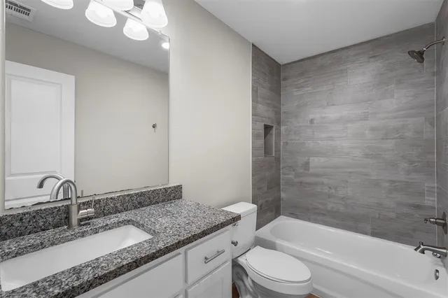 a bathroom with a granite countertop sink a toilet and bathtub