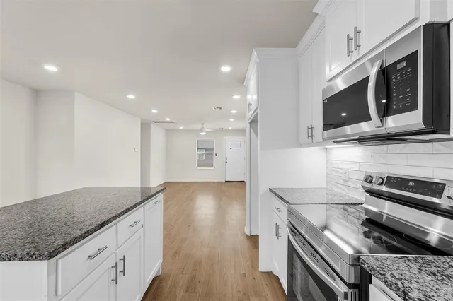 a kitchen with stainless steel appliances granite countertop a stove and a microwave