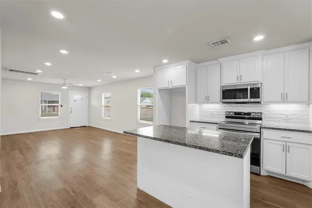 a kitchen with stainless steel appliances granite countertop a stove a sink and a microwave