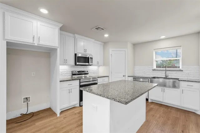 a kitchen with stainless steel appliances granite countertop a sink stove microwave and refrigerator