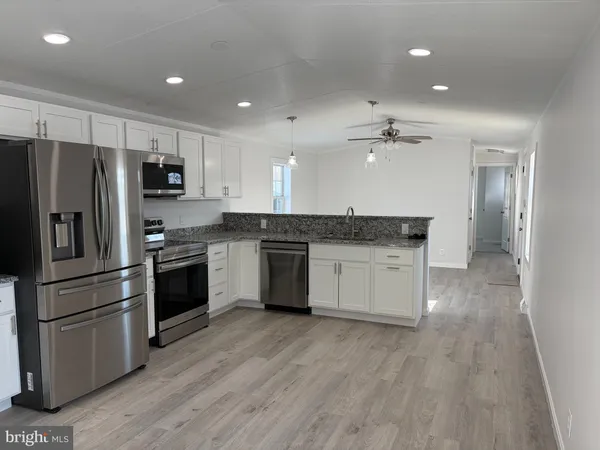 a kitchen with granite countertop a refrigerator and a stove top oven