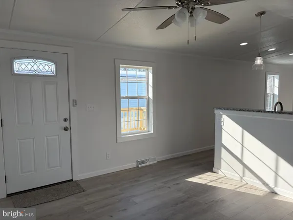 an empty room with wooden floor fan and windows