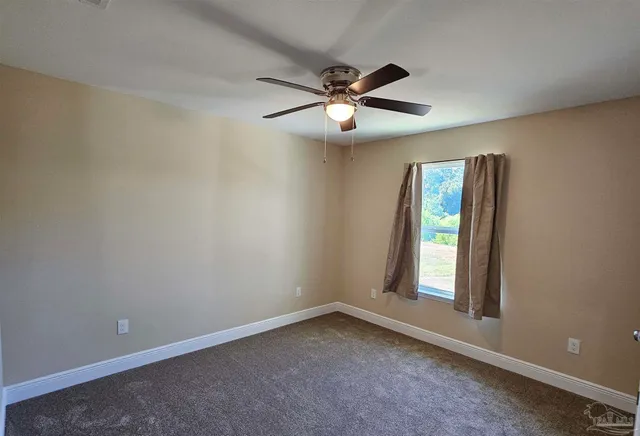 an empty room with chandelier fan and windows