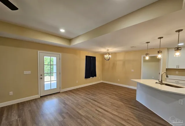 a view of an empty room with wooden floor and a ceiling fan
