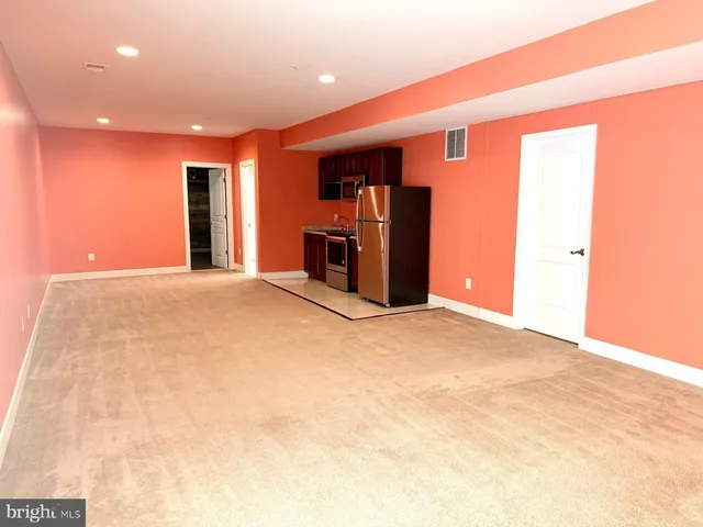 a view of an empty room with furniture and a window