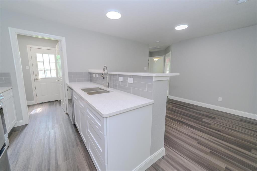 809 Wilcox Street McKinney, TX 75069 - Photo 6 of 26 Kitchen with a peninsula, dark wood-type flooring, backsplash, white cabinets, and light stone countertops