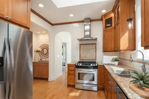 a kitchen with stainless steel appliances granite countertop a refrigerator a stove and a sink with wooden floor