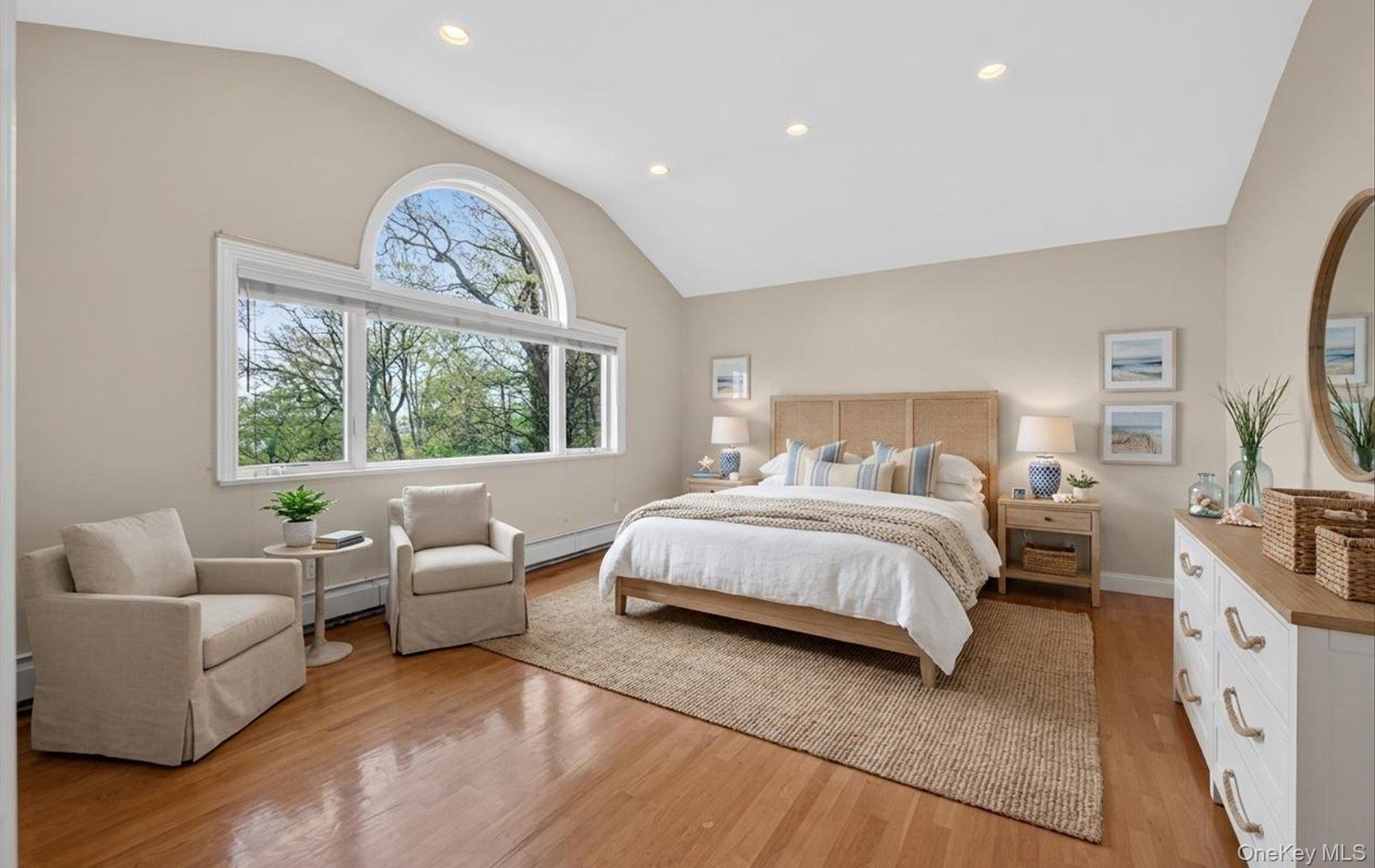 16 East Slope Road Bayville, NY 11709 - Photo 26 of 48 Staged primary bedroom with vaulted ceiling bedroom featuring expansive window with arched transom, recessed lighting, and wood-finish flooring