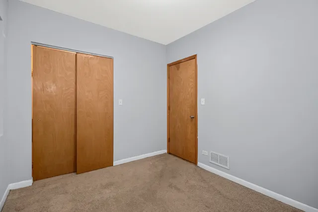 a view of an empty room with closet and a window