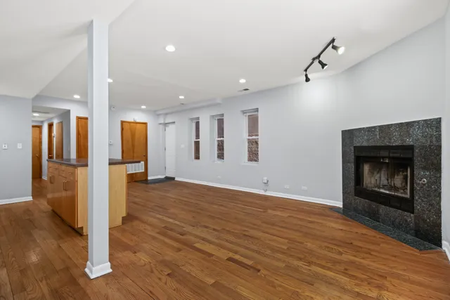 a view of an empty room with wooden floor a fireplace
