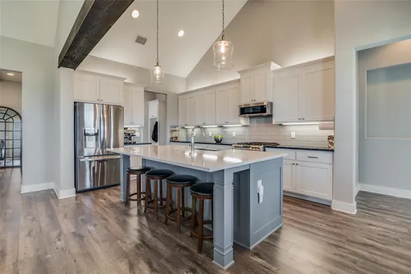 a kitchen with stainless steel appliances granite countertop a stove top oven a refrigerator a sink and a dining table with wooden floor