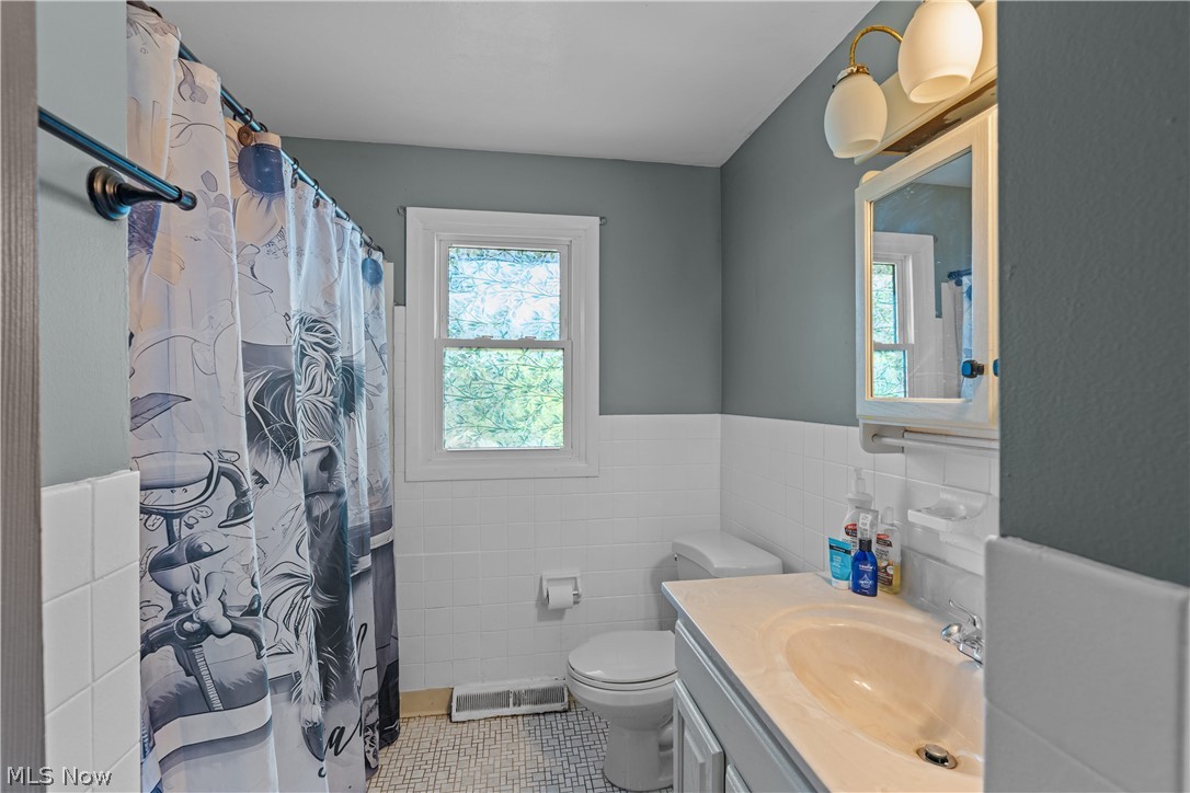 13548 Holland Road Brook Park, OH 44142 - Photo 23 of 27 Bathroom featuring a single window, white tiled walls, a vanity with an integrated sink, a wall-mounted medicine cabinet, and a two-light fixture
